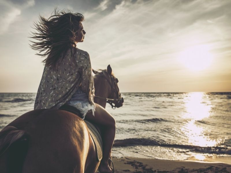 woman horseback riding in sunset