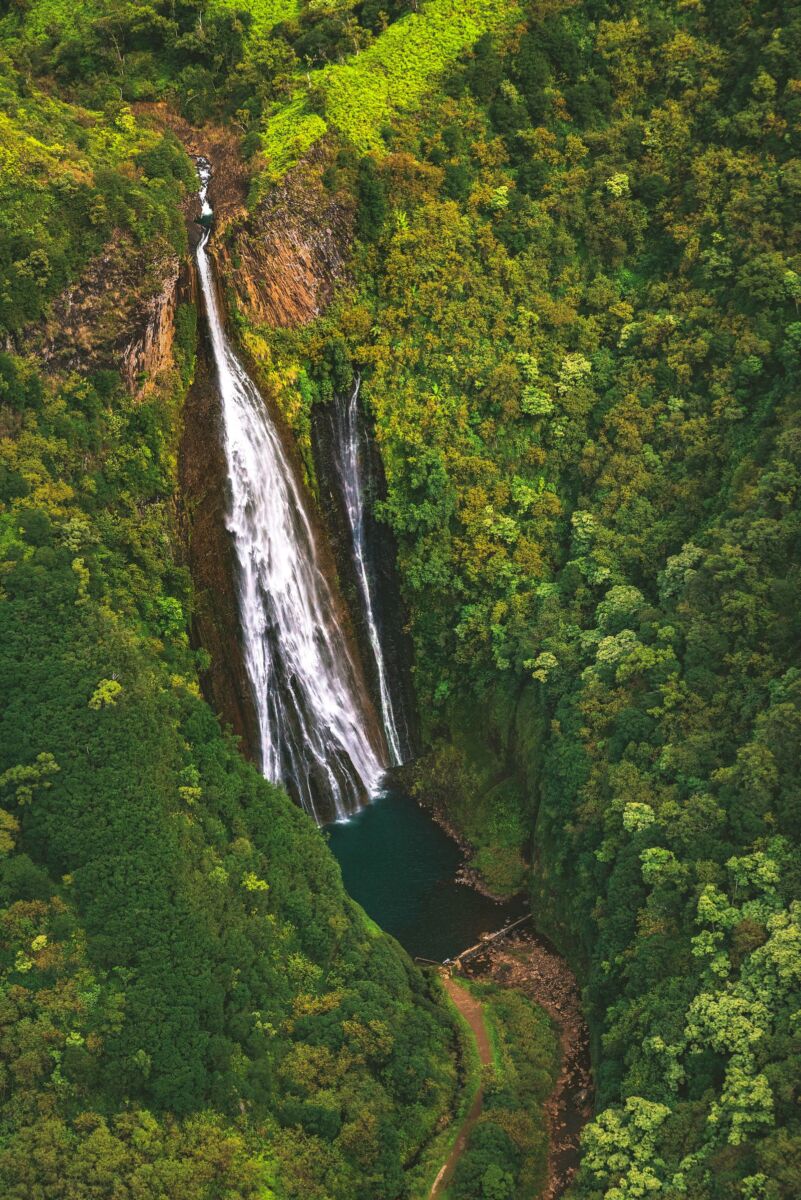 Manawaipuna Falls in Kauai, Hawaii. A large waterfall surrounded by lush landscapes